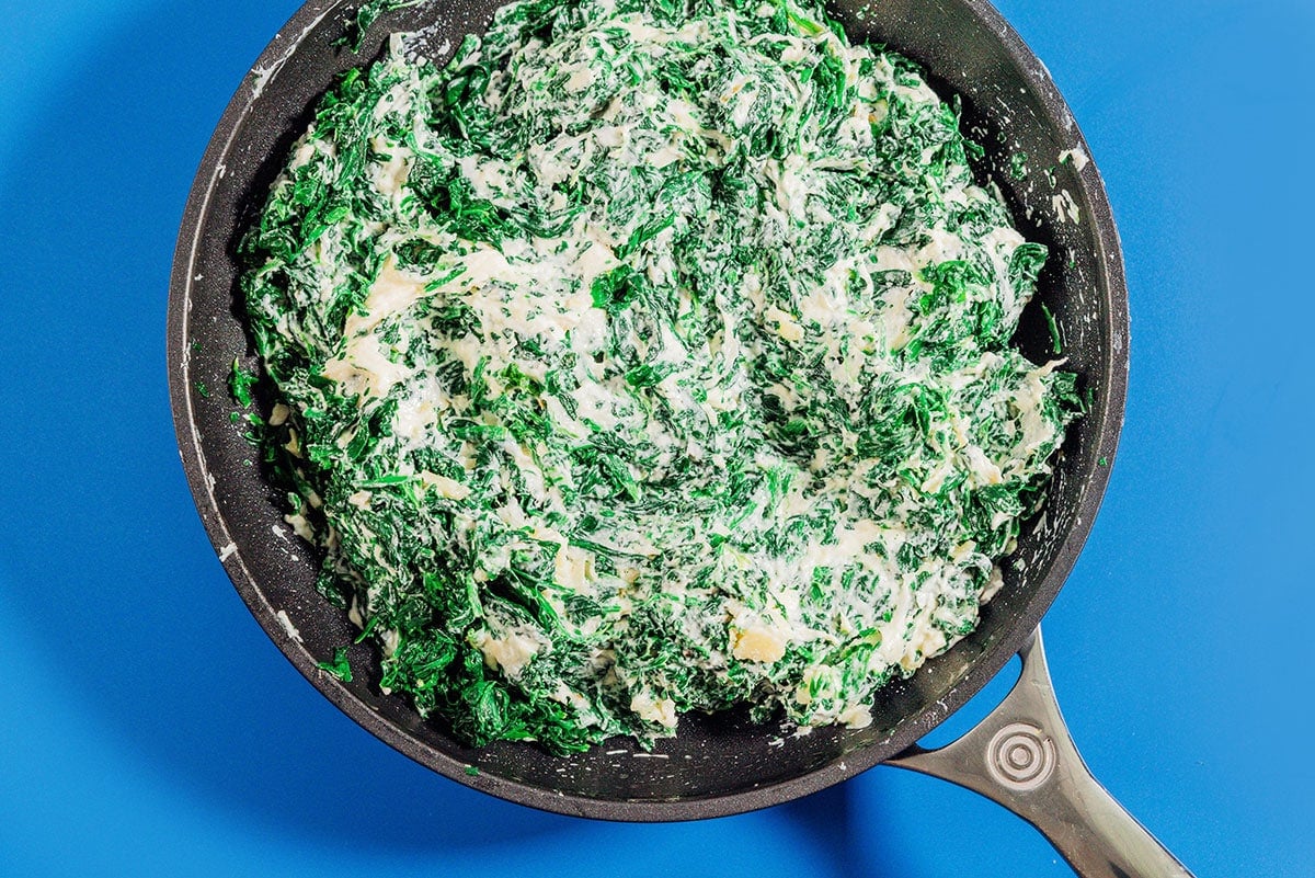 Mixing spinach with green cheese.