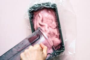 Pouring pink popsicle mixture into loaf pan.