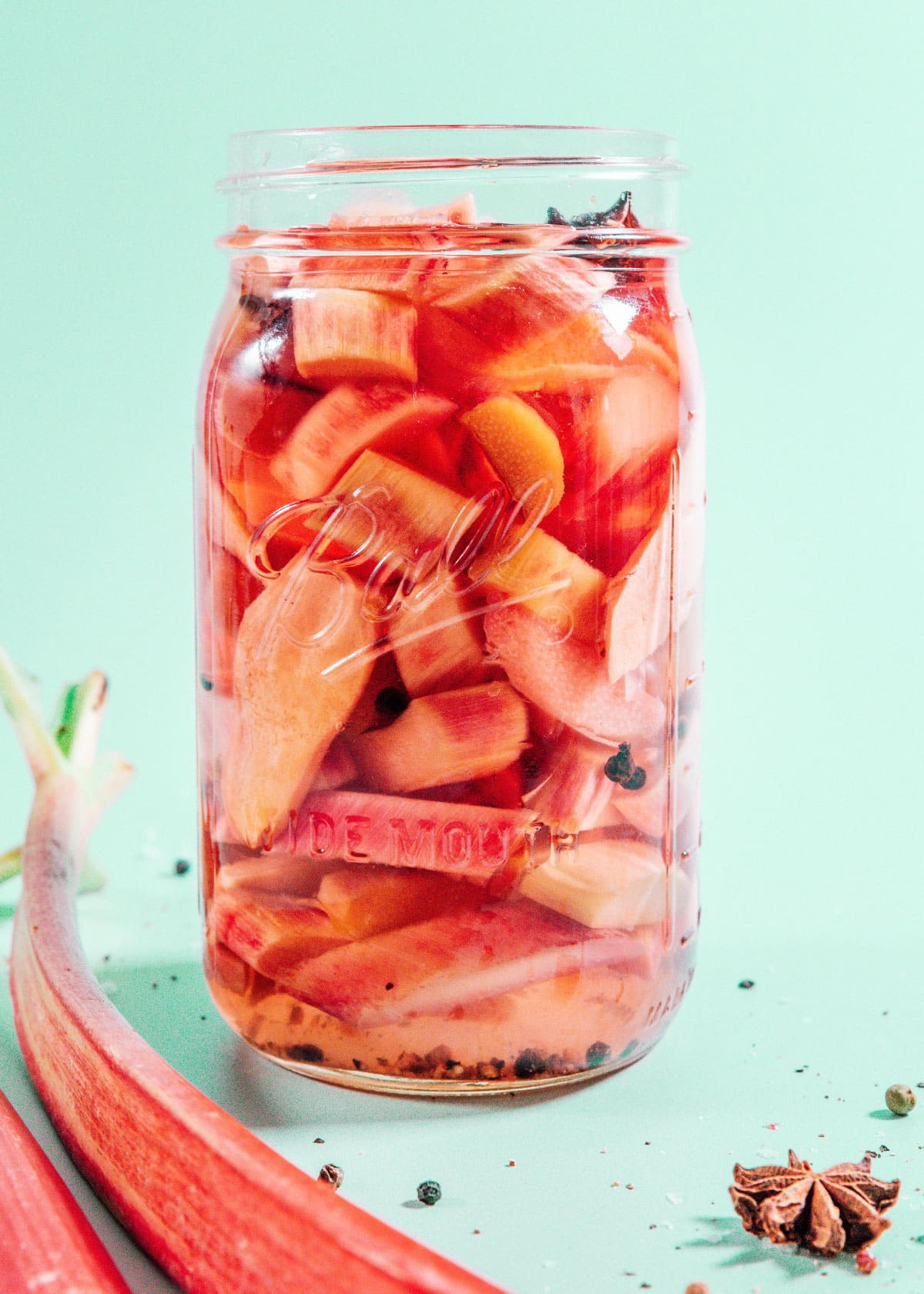 Pickled rhubarb in a mason jar on teal background.