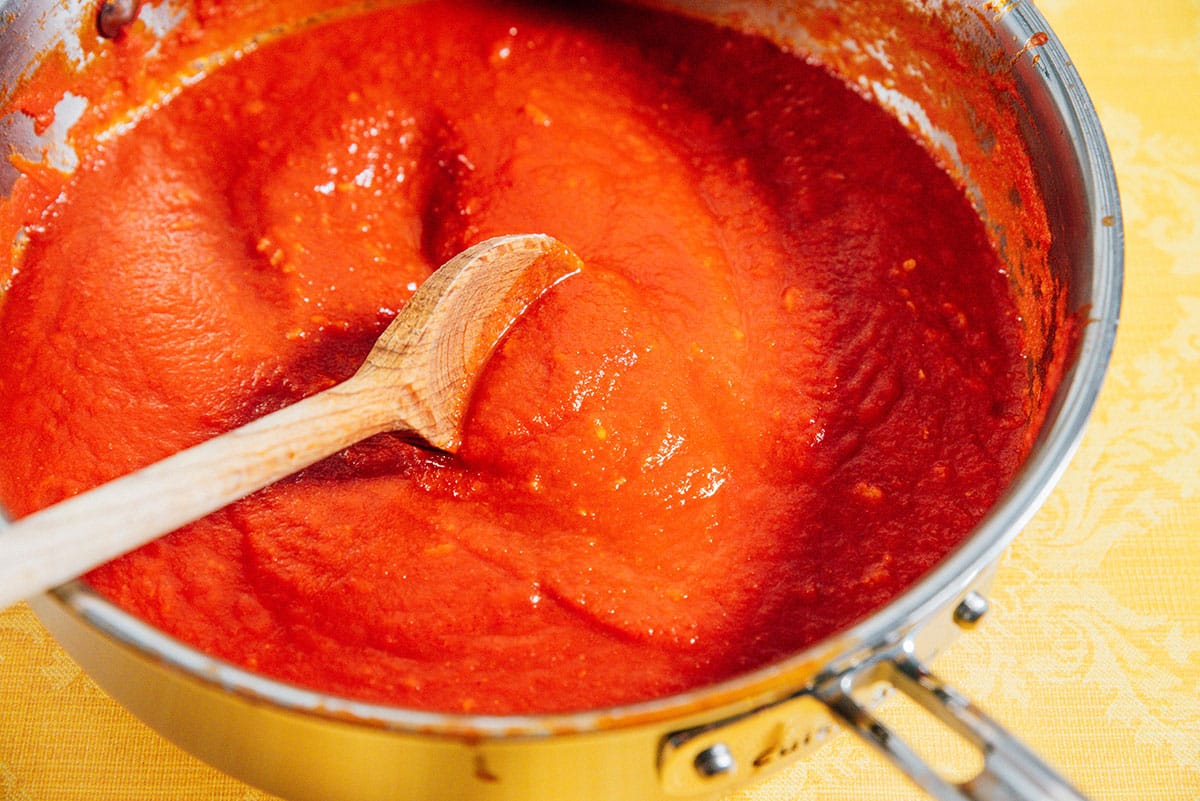 Stirring pasta sauce in a pan.