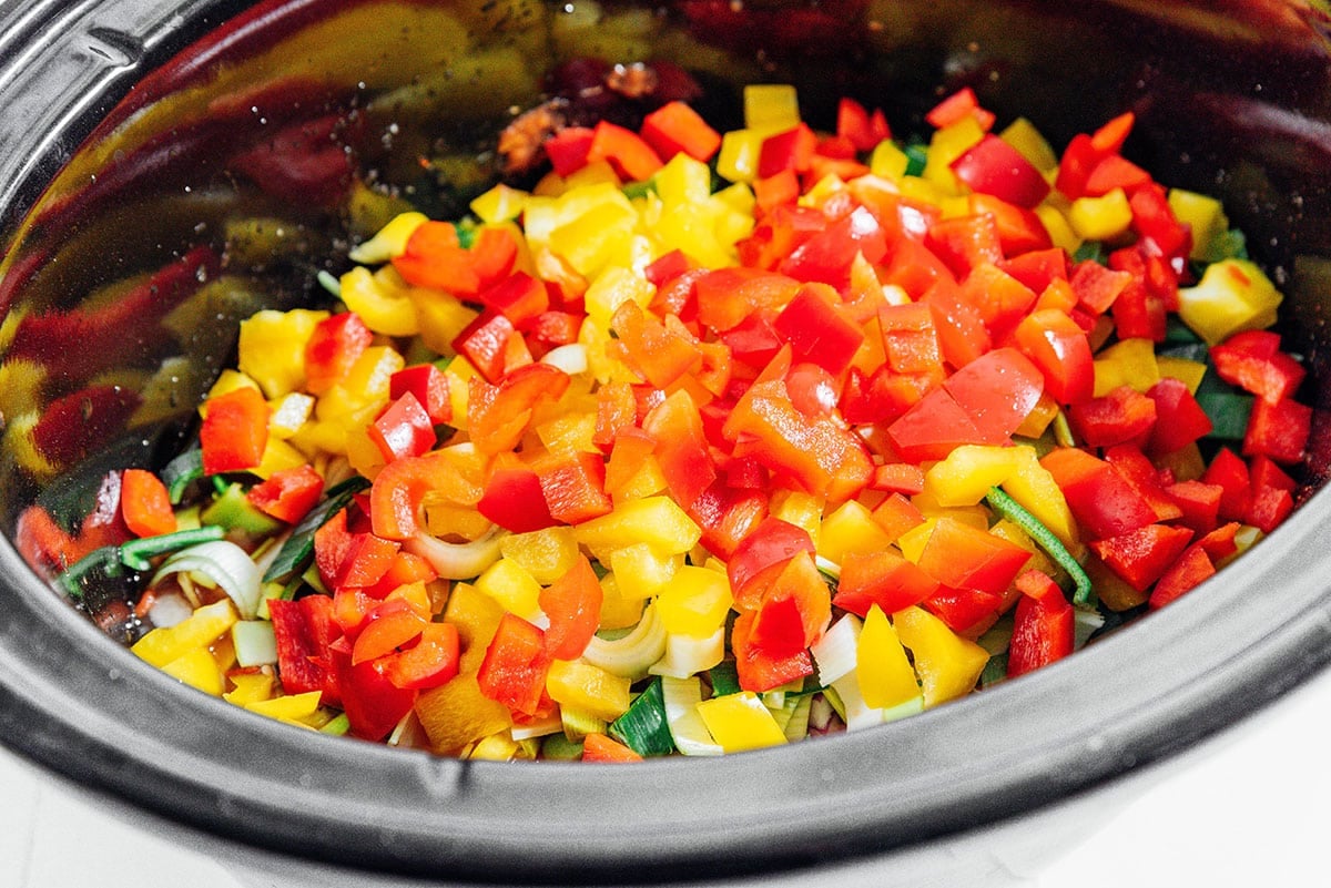 Bell peppers and other veggies in a slow cooker.