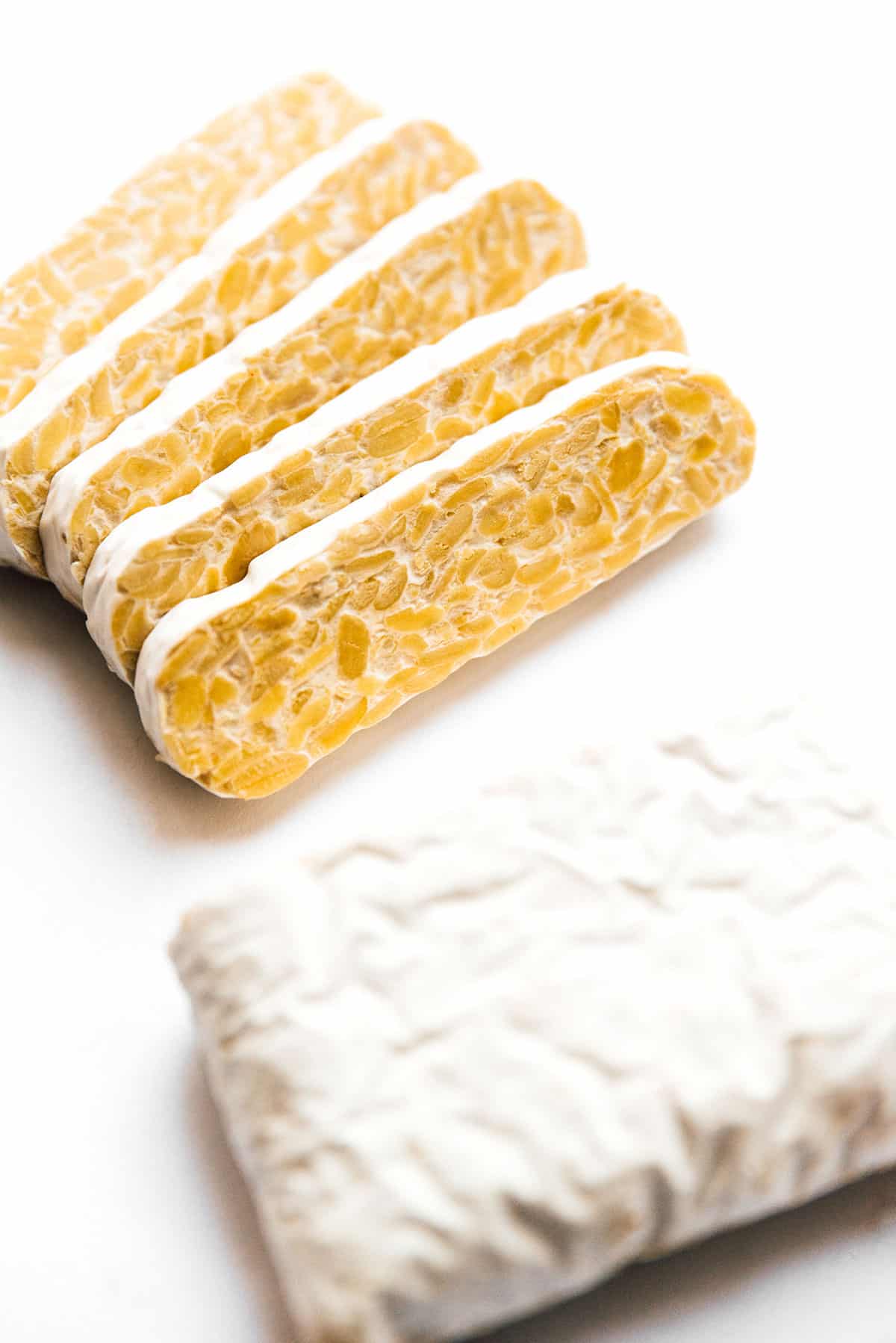Picture of tempeh block on white background - Let's talk about what you need to know when cooking with tempeh (including what it is, the difference between tofu and tempeh, and how to cook it)!