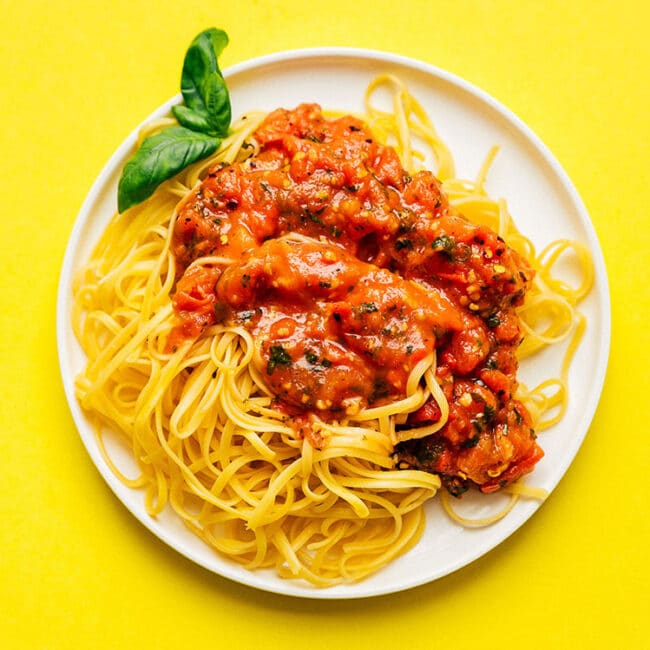 Chunky fresh marinara sauce on a plate of spaghetti.