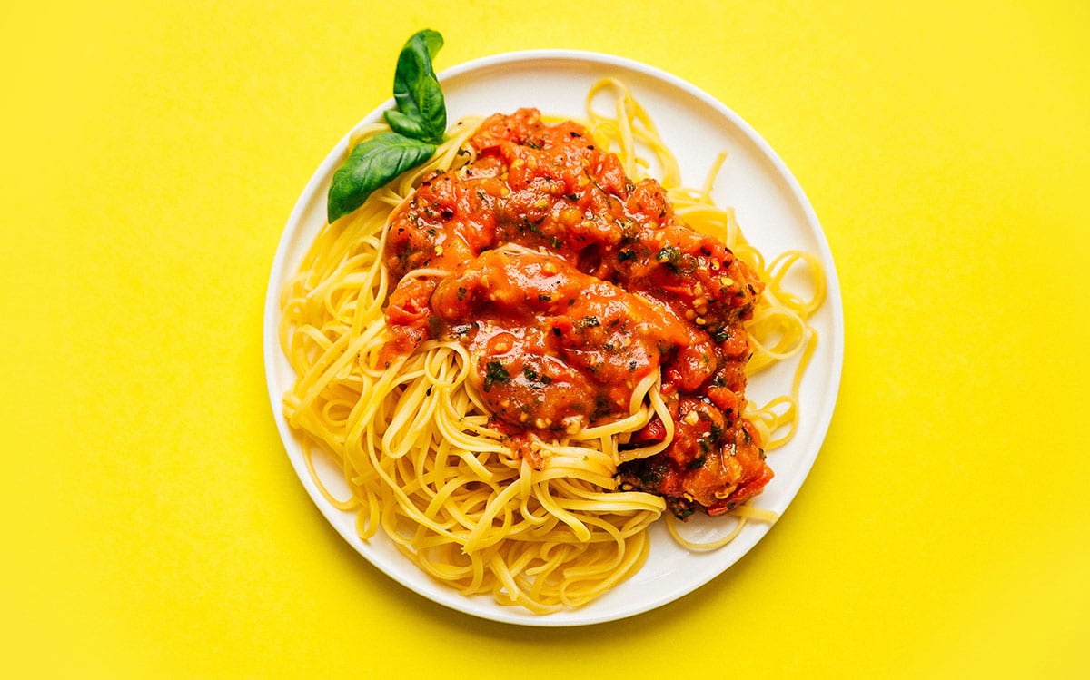 Chunky fresh marinara sauce on a plate of spaghetti.