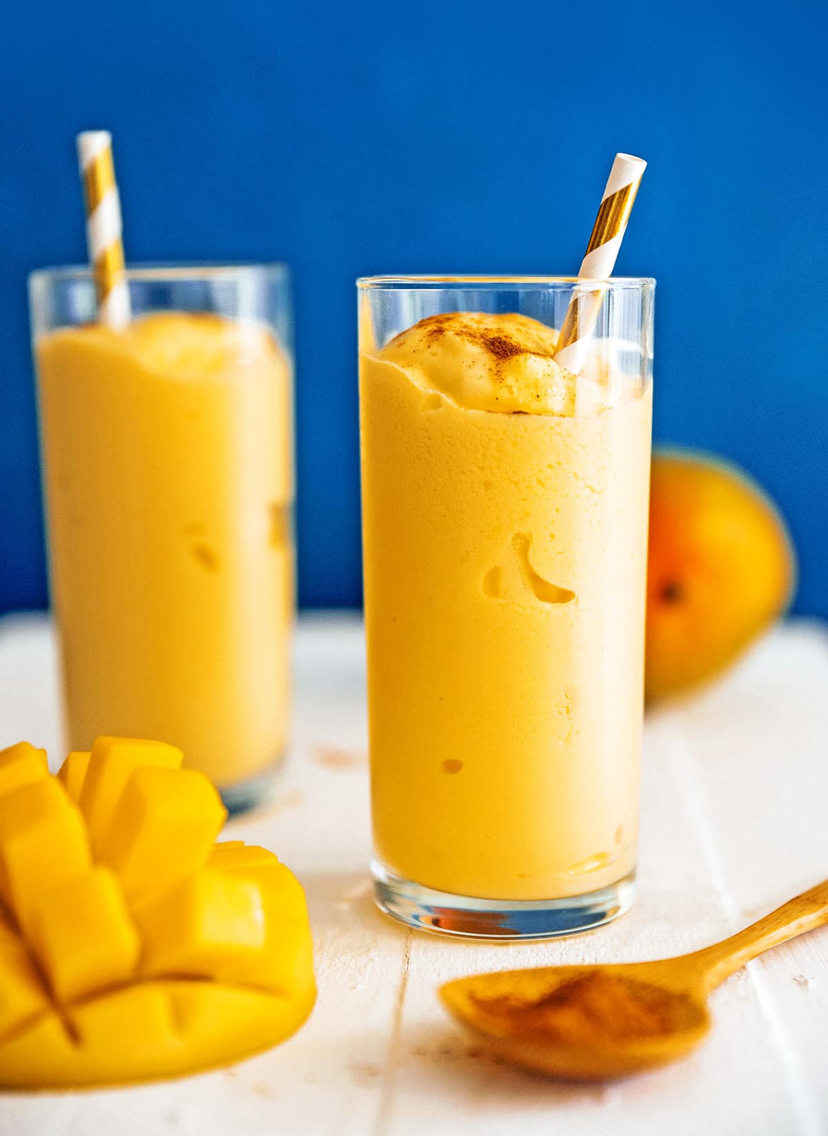 Mango lassi in a glass with a striped straw.