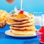 Pineapple upside down pancakes stacked with a cherry on top.