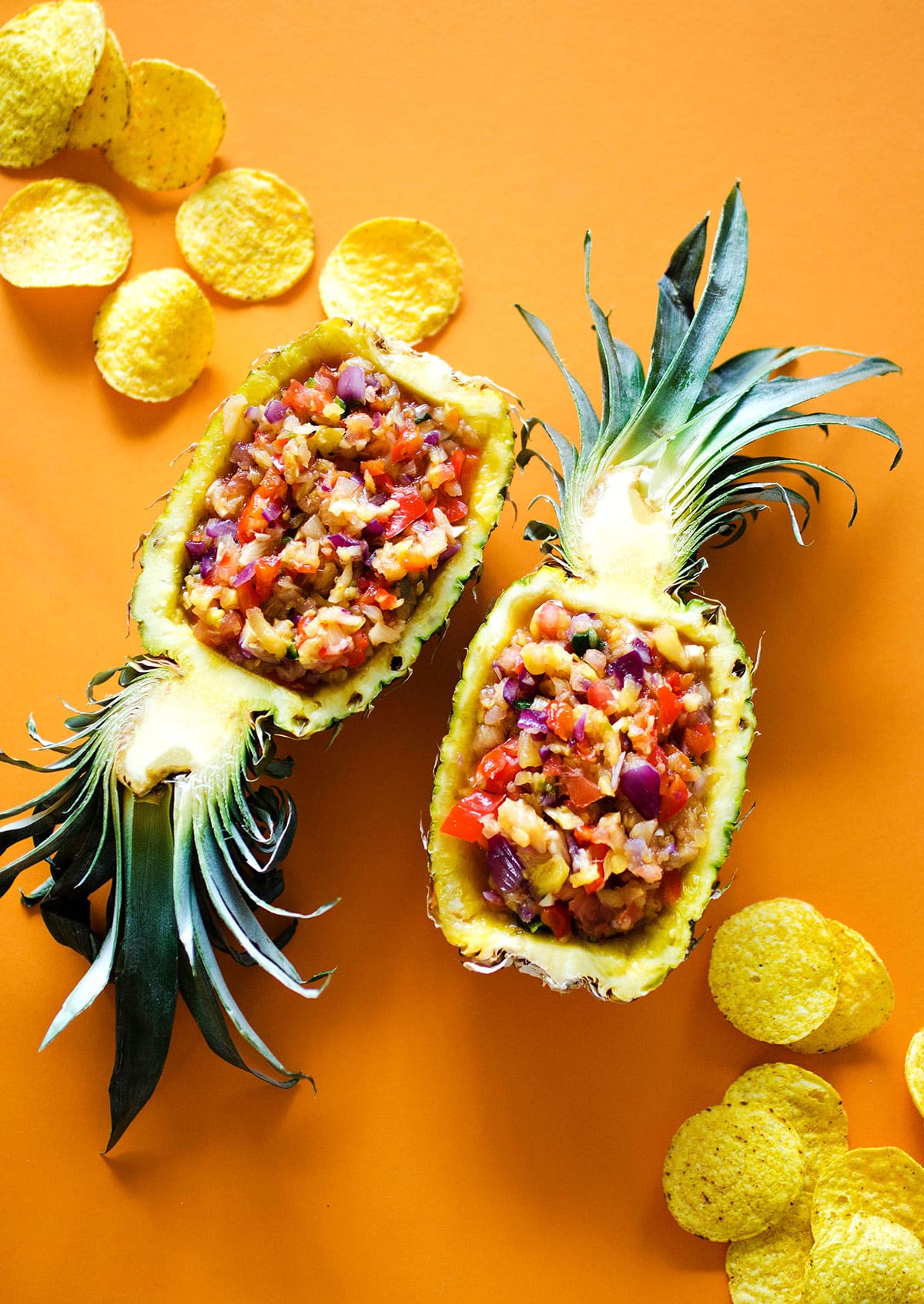 Pineapple salsa served in the pineapple on an orange background.