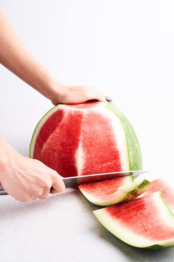 Cutting the rind off a watermelon.