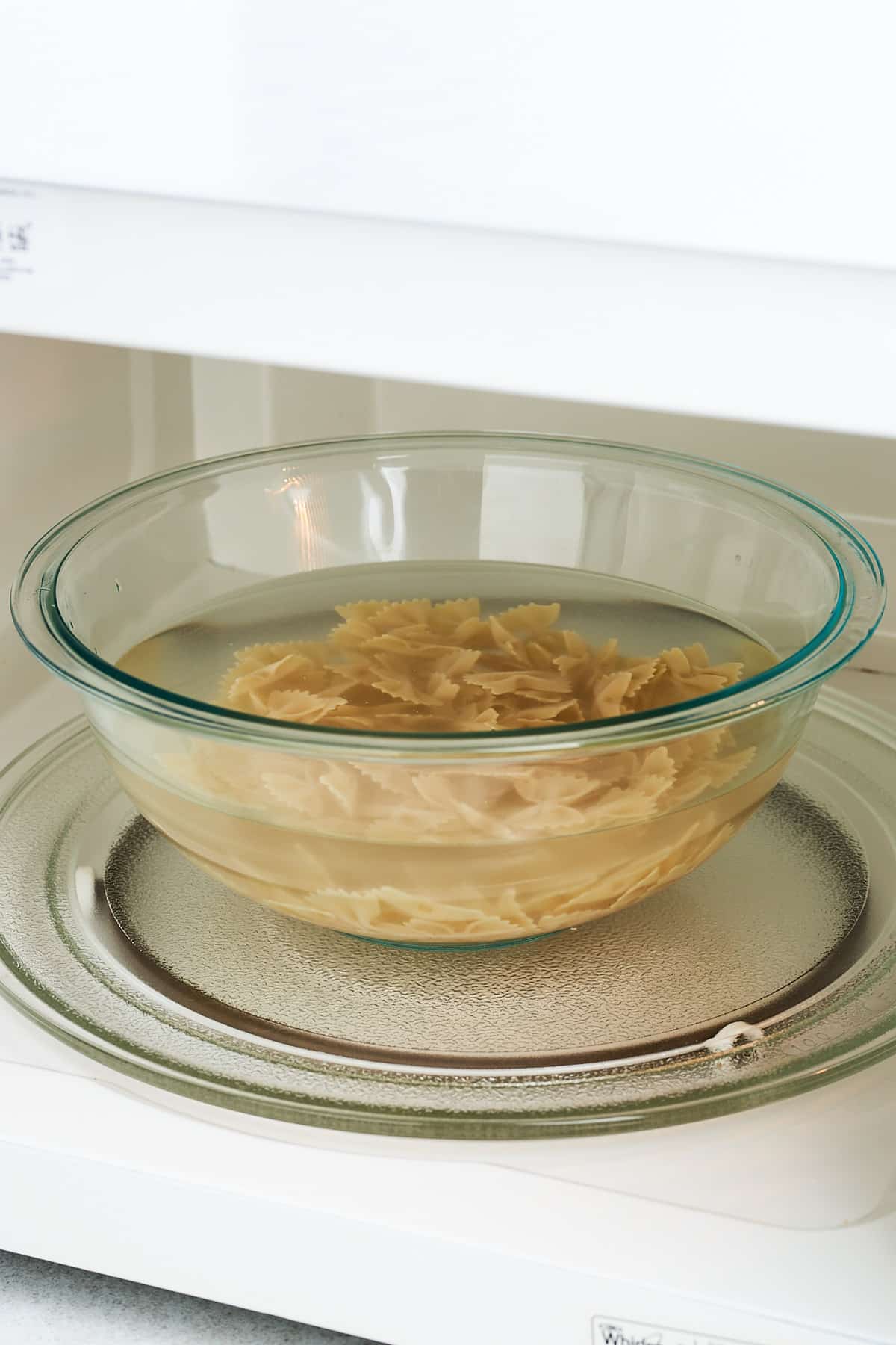 Pasta in a bowl of water in the microwave.