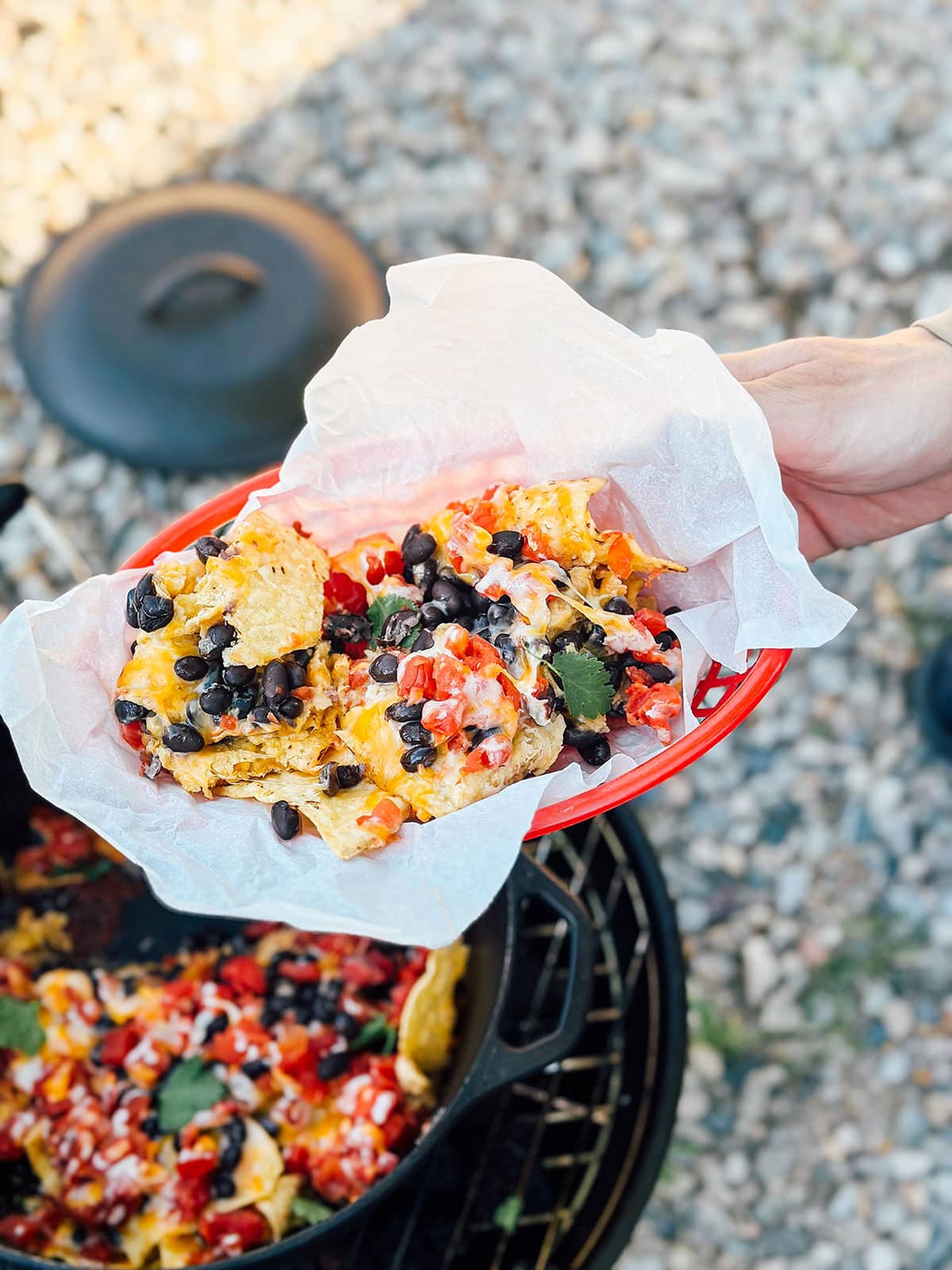 Hand holding plate of campfire nachos.