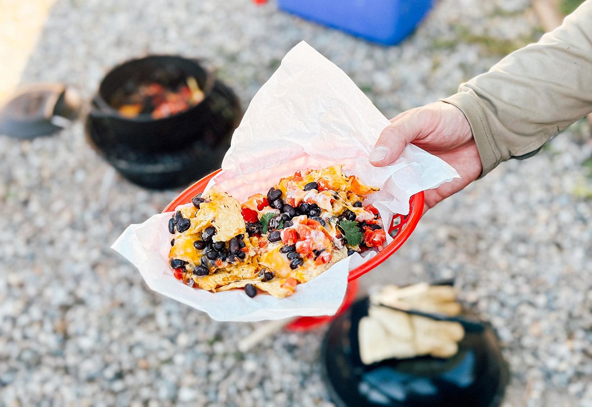 Hand holding plate of campfire nachos.