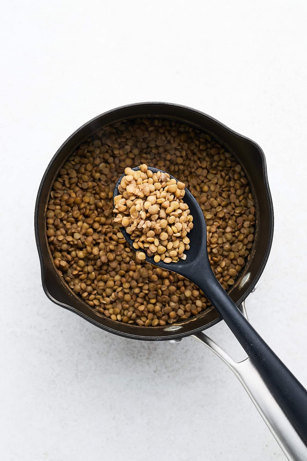 Cooked lentils on a serving spoon.