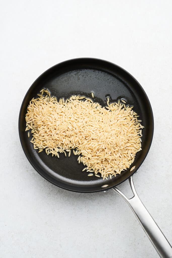 Orzo in a pan with butter.