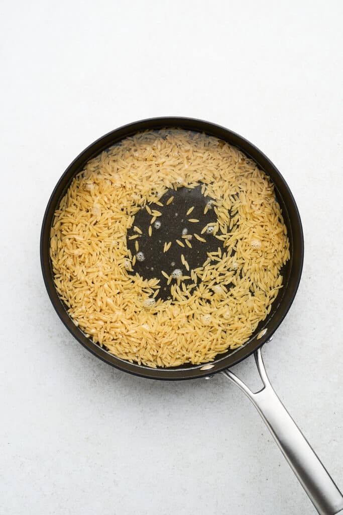 Orzo with water in a pan.
