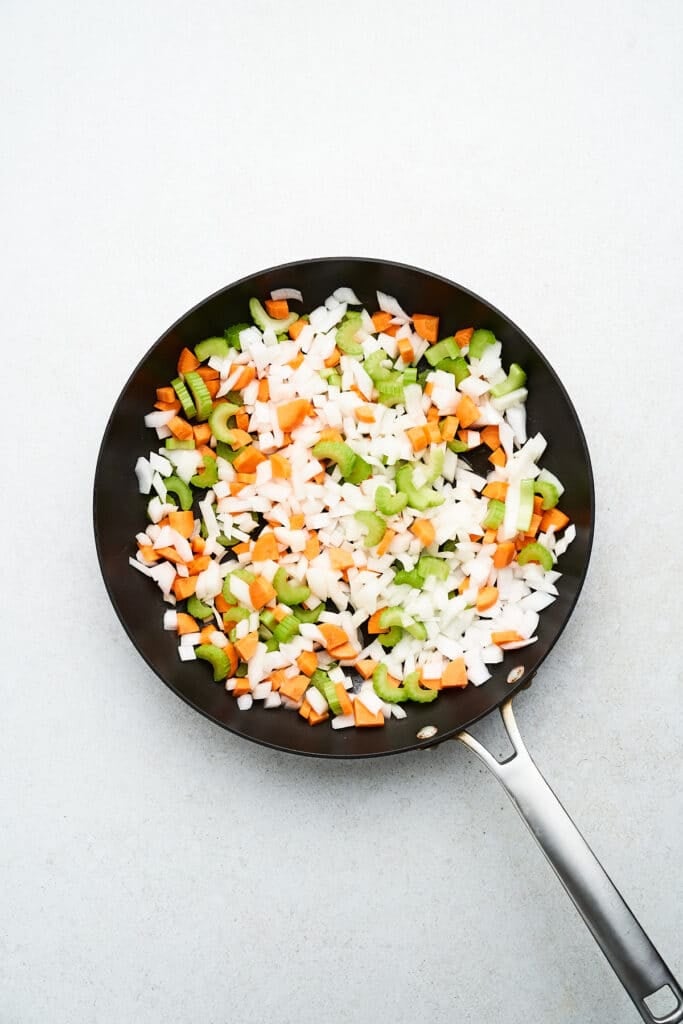 Onions, carrots, and celery in a pan.