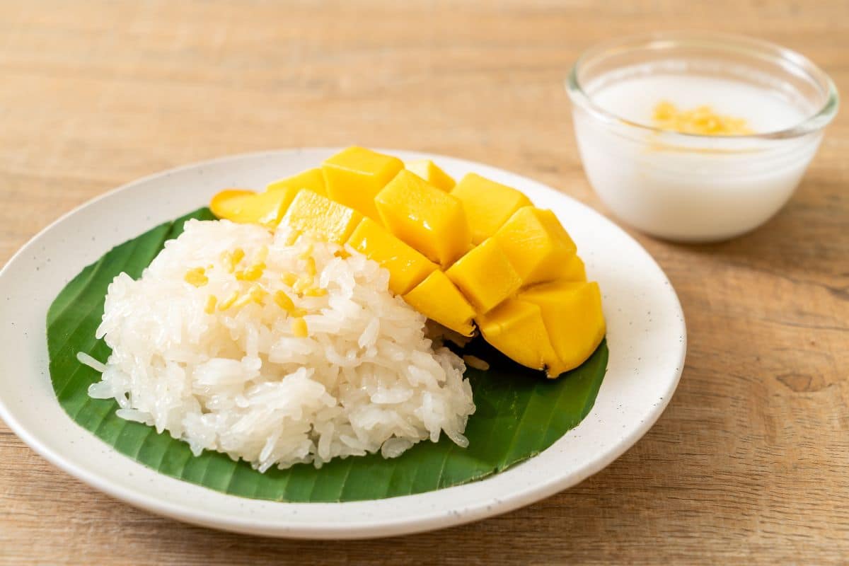 Coconut rice on a plate next to mango.