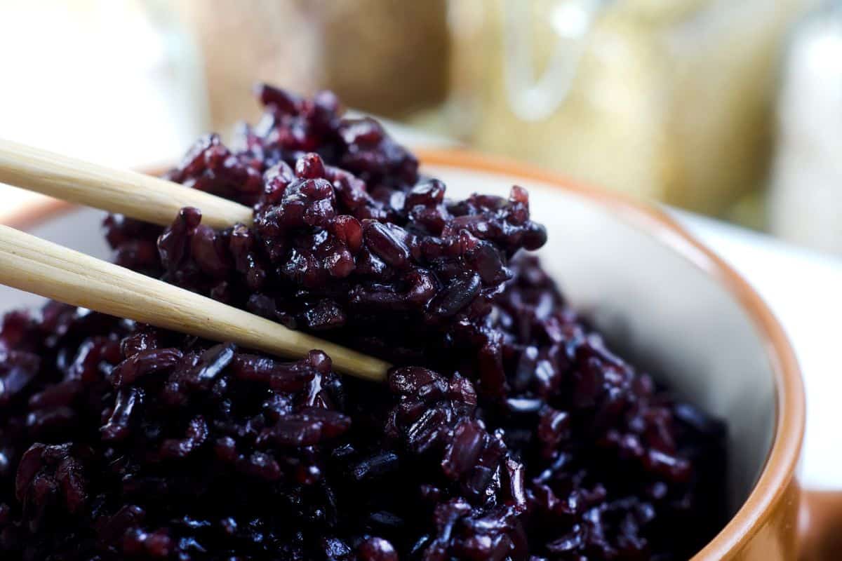 Glutinous black rice being picked up by chop sticks.