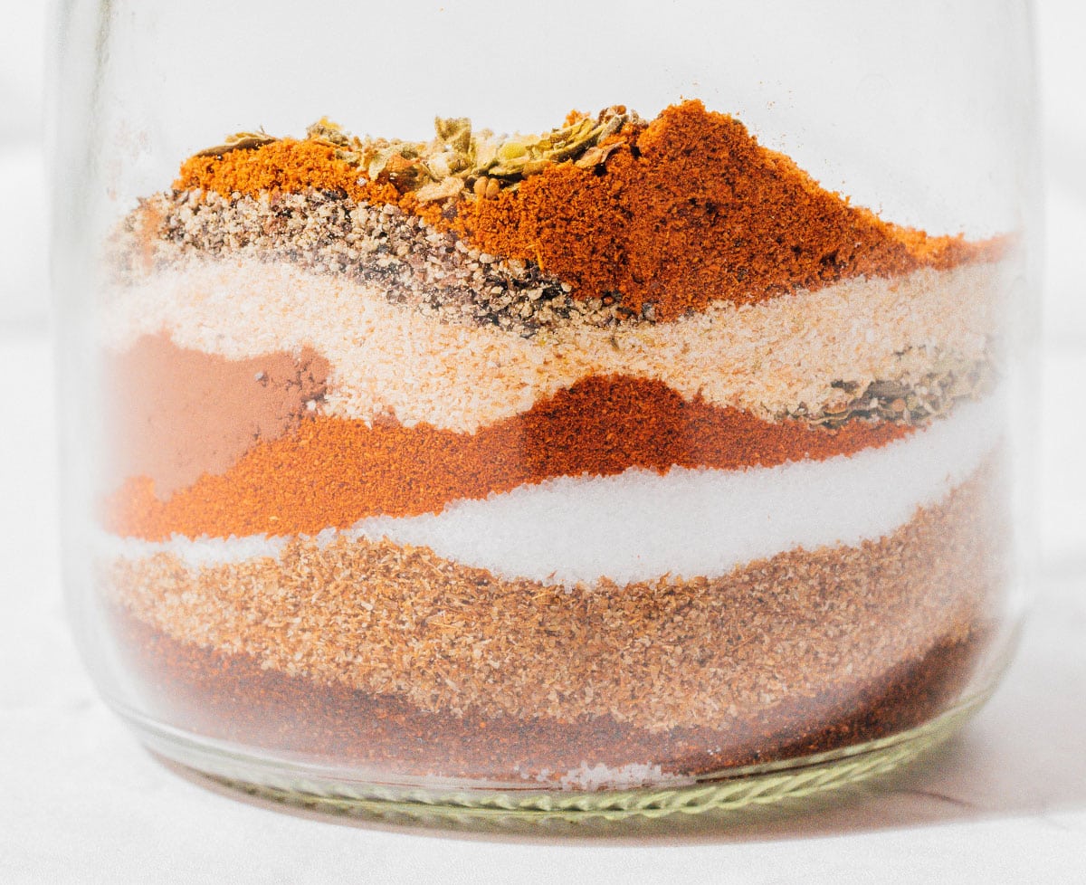 Spices for making chili seasoning layered in a glass.