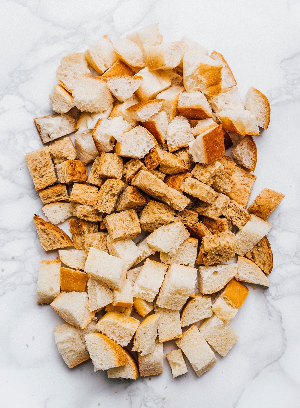 Cut up bread on a marble table for croutons.