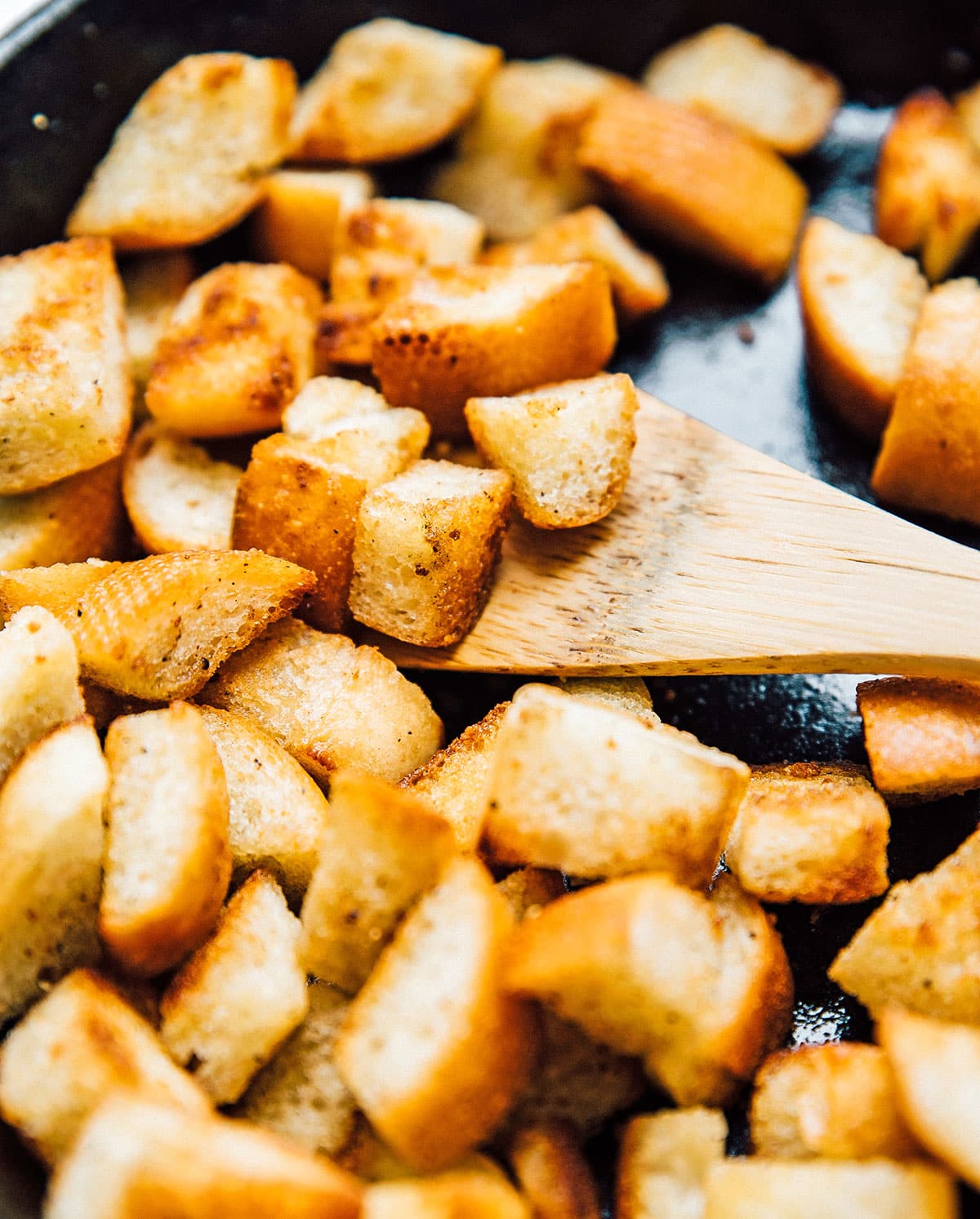 Croutons in a pan with a spoon.