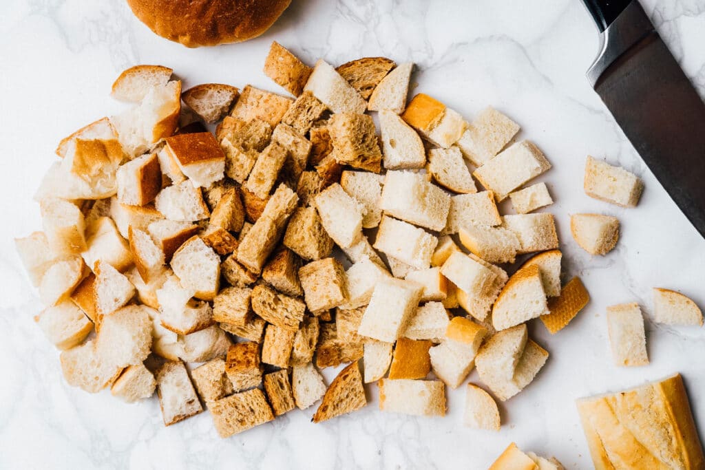 Cut up bread on a marble table for croutons.