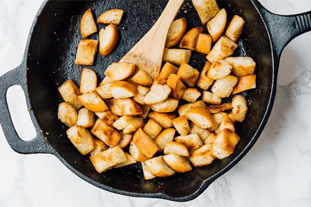 Making homemade croutons in a cast iron skillet.
