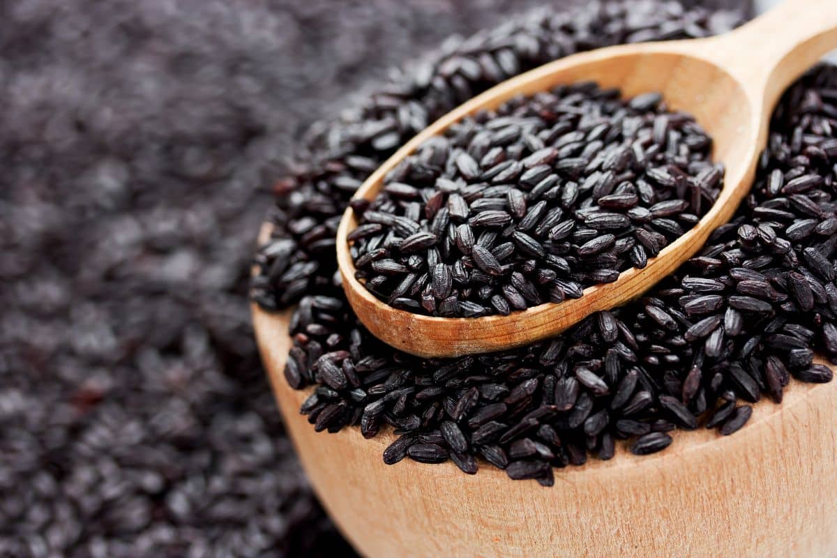 Italian black rice in a wood bowl with a wood spoon.