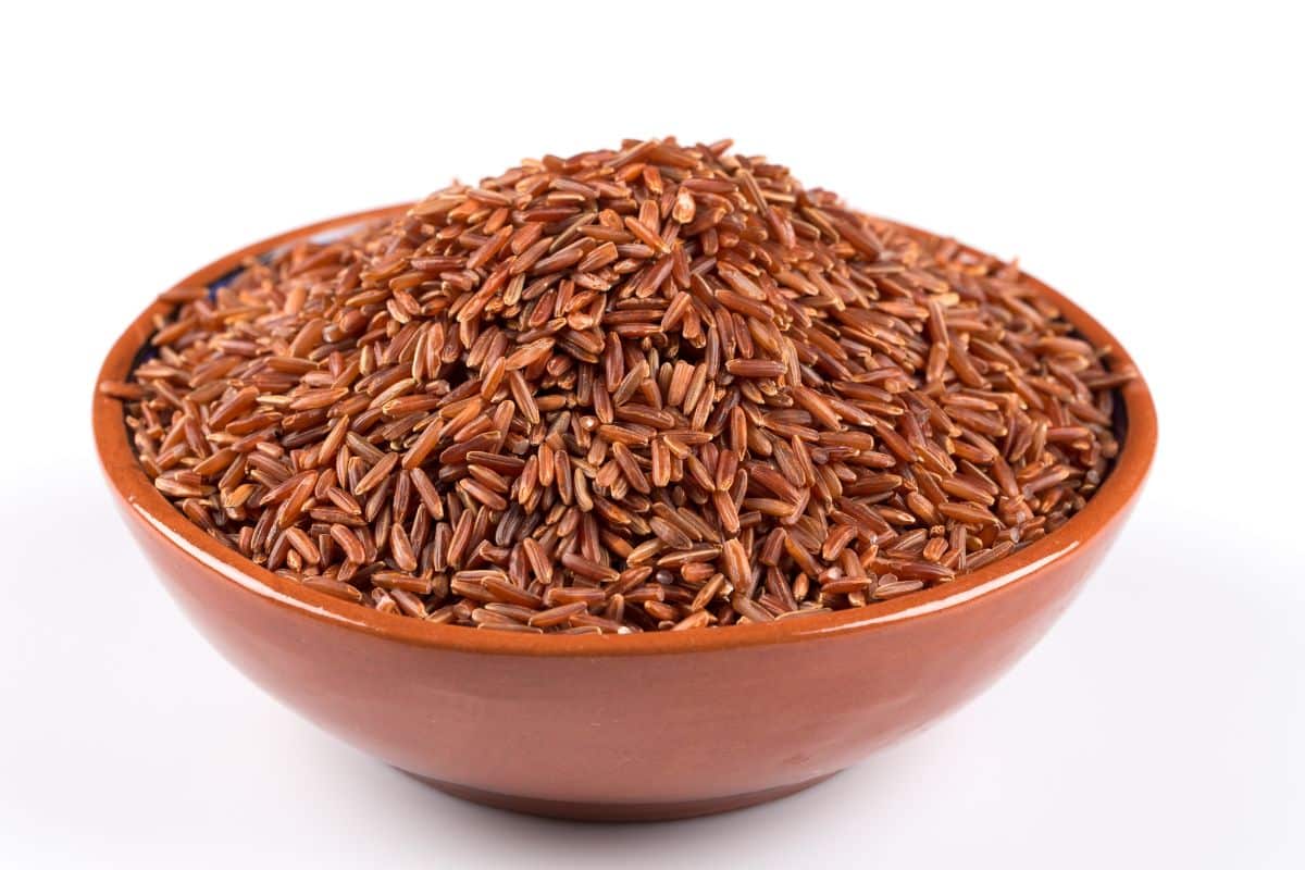 Red rice in a red bowl on a white background.