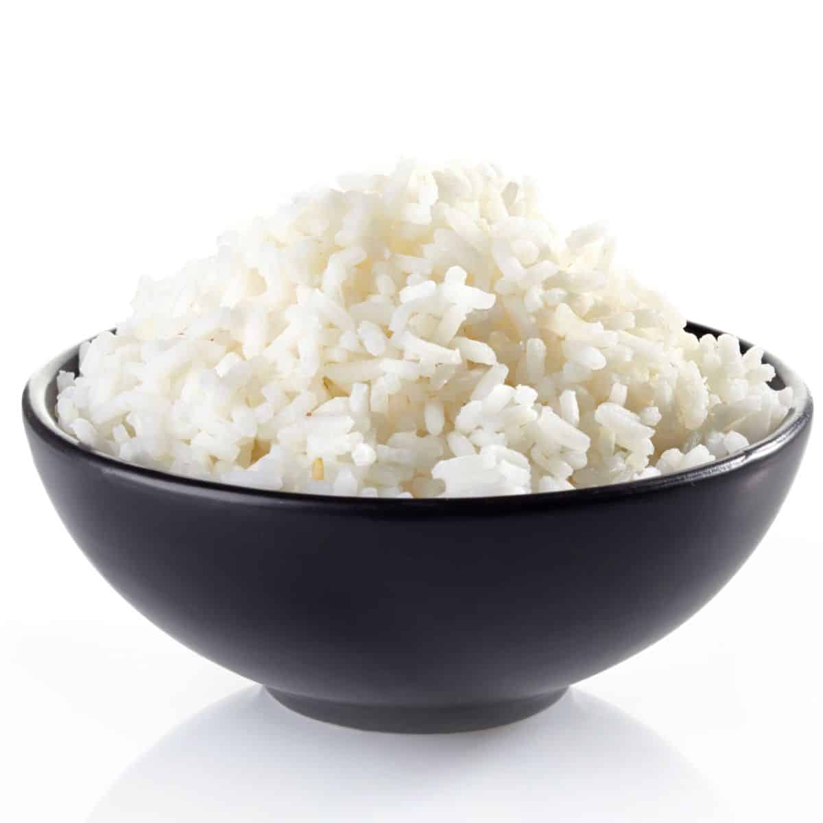 Sticky rice in a black bowl on a white background.