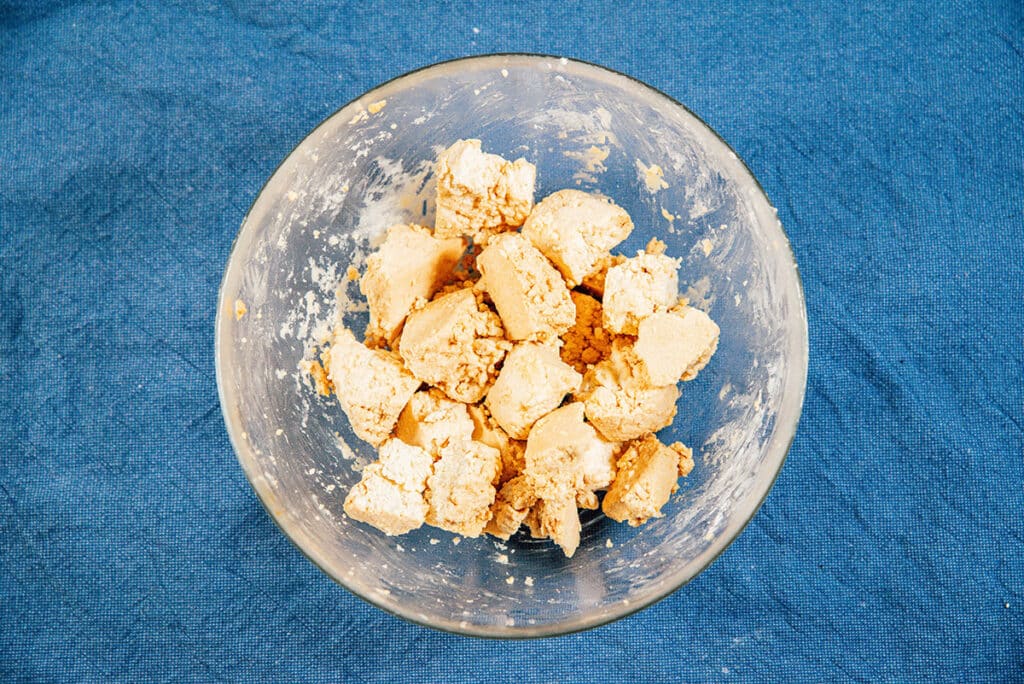 Torn pieces of tofu in a glass bowl.