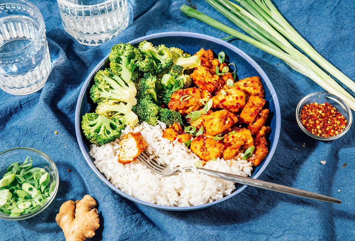 Teryaki tofu with rice and broccoli in a blue bowl.