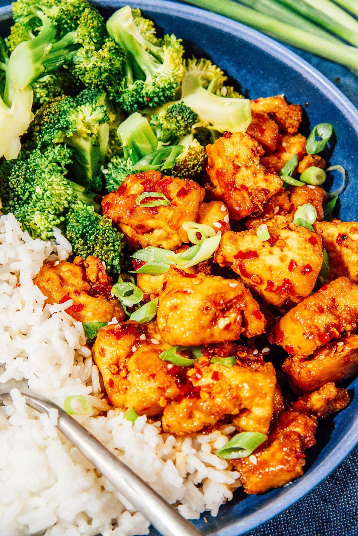 Teryaki tofu with rice and broccoli in a blue bowl.