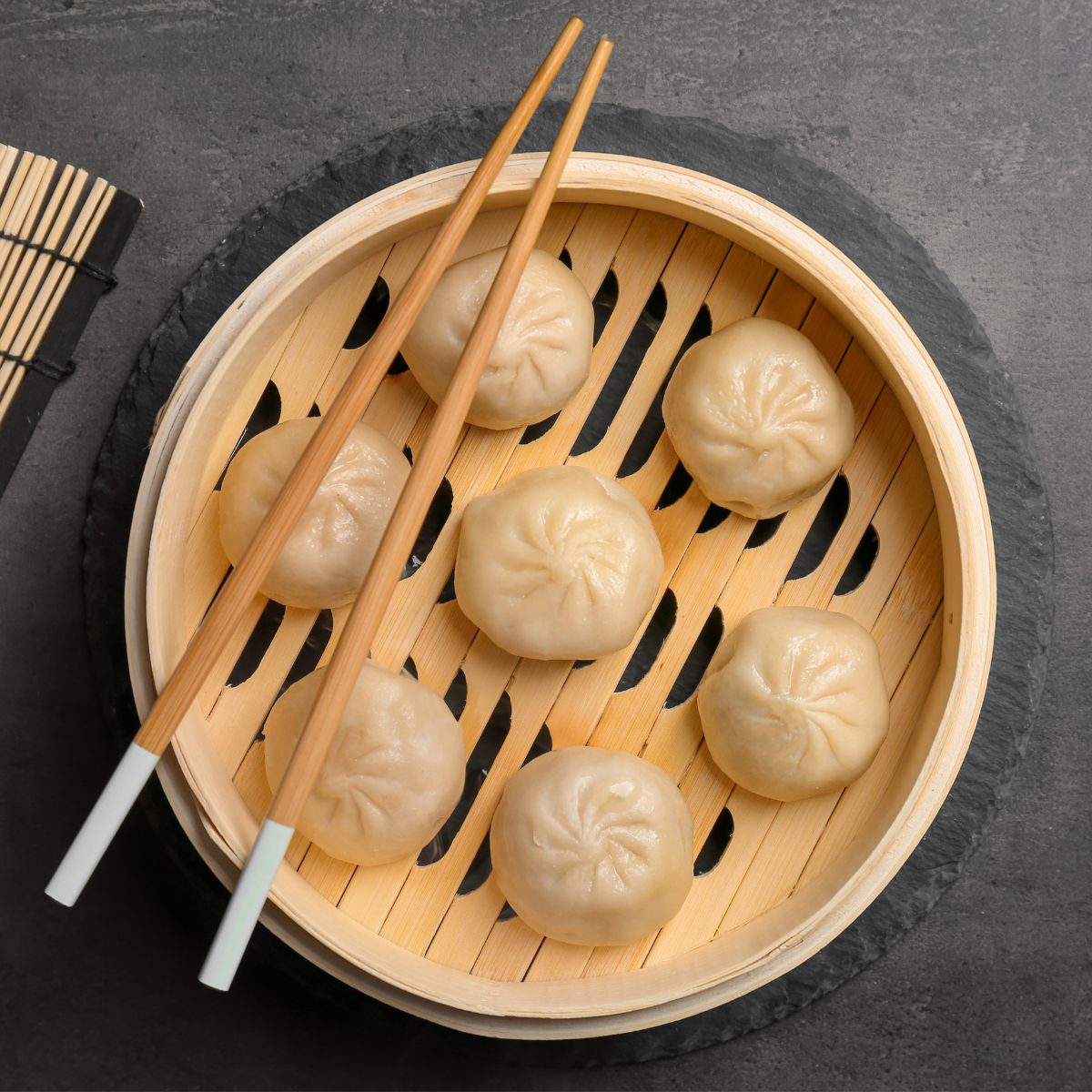 Xiaolongbao in a steamer with chopsticks.