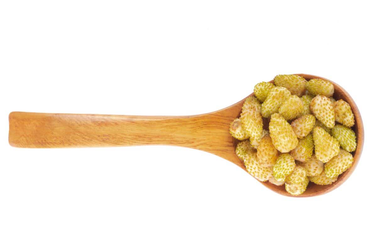 Yellow strawberries on a spoon on a white background.