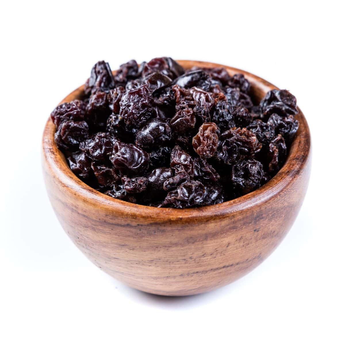 Zante currants in a wood bowl on a white background.