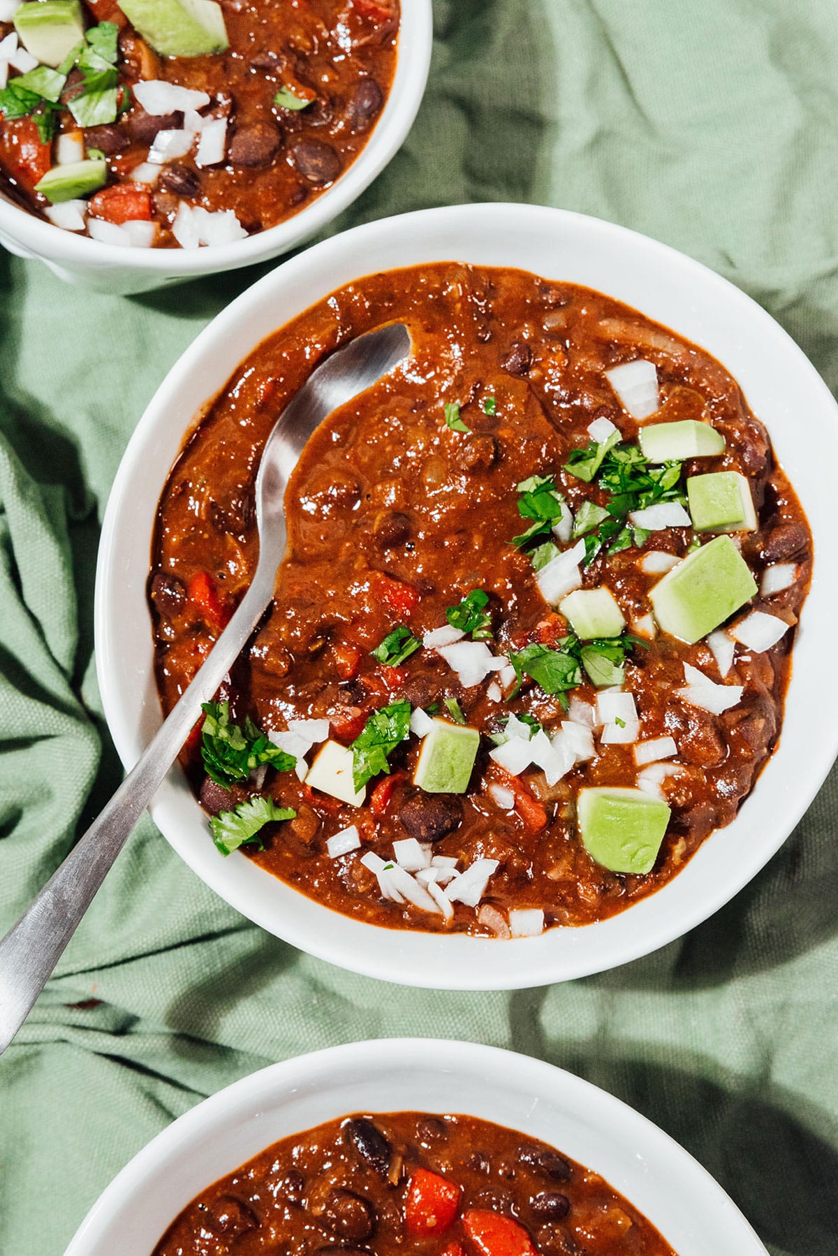 Black bean chili with avocado and onions in a bowl.