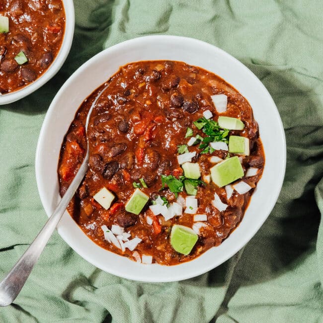 Black bean chili with avocado and onions in a bowl.