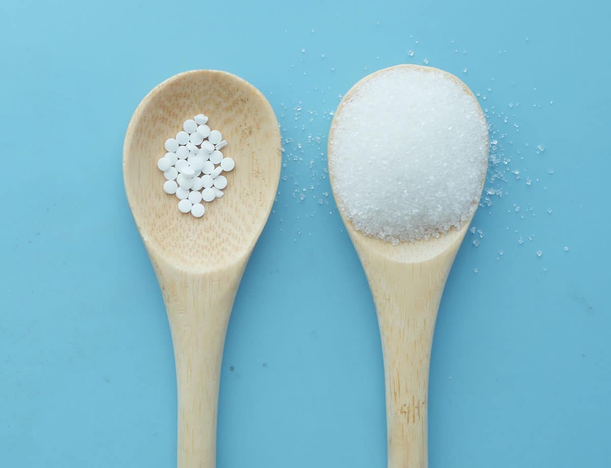 Fake sugar vs normal sugar on spoons.