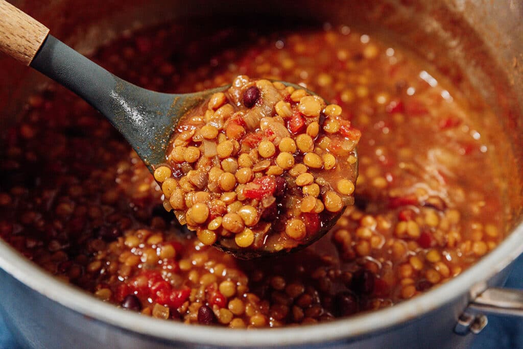 Ladling lentil chili out of a bowl.