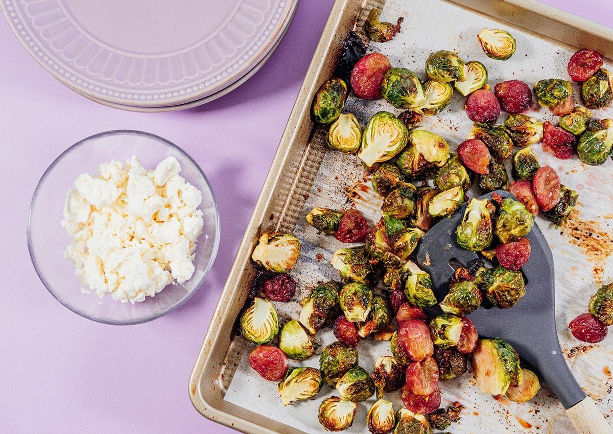 Roasted Brussels sprouts with grapes on a baking sheet.