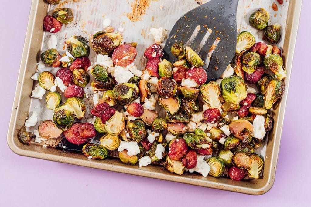 Roasted Brussels sprouts with grapes on a baking sheet.