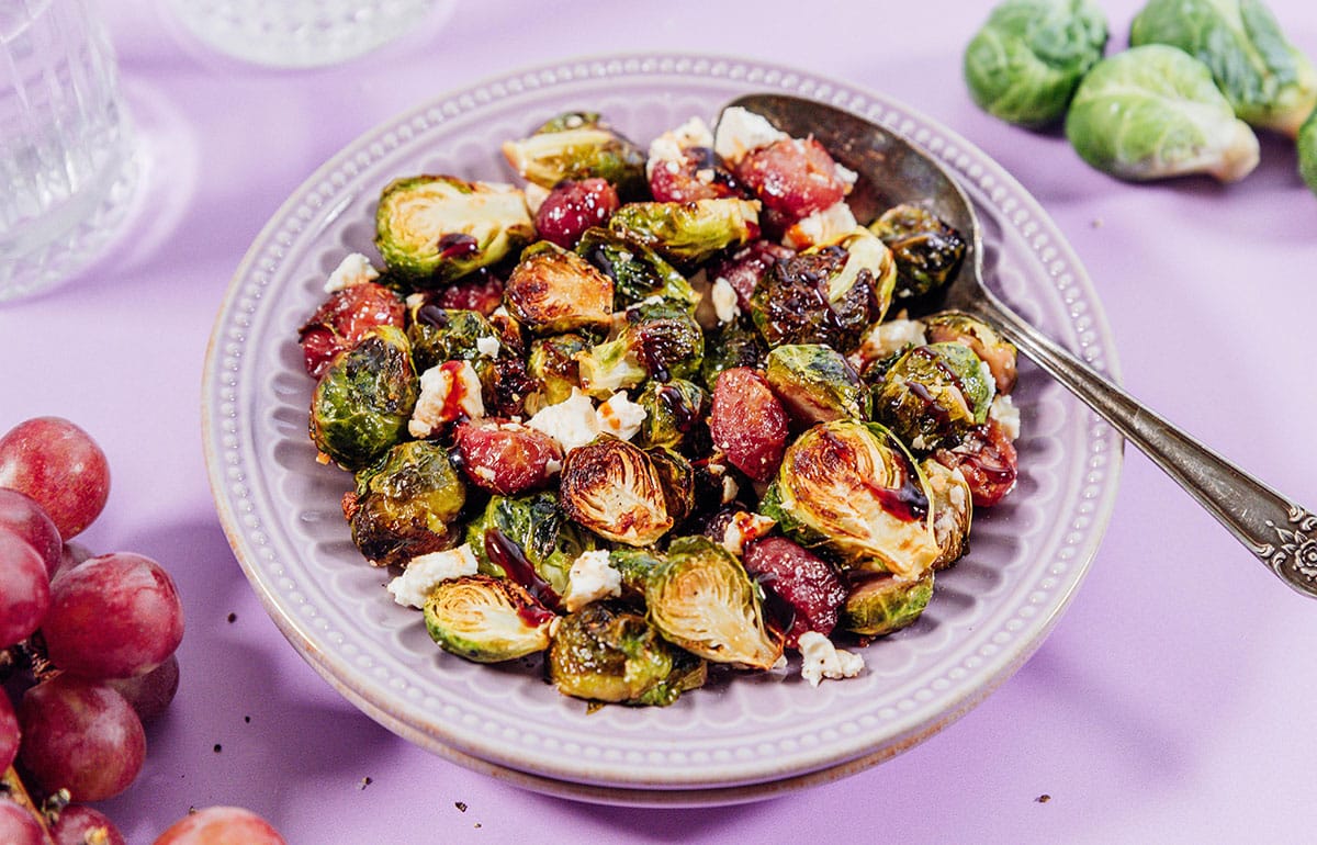 Roasted Brussels sprouts with grapes and feta on a plate.