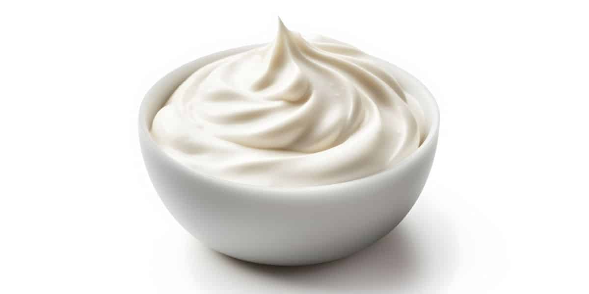 A bowl of sour cream on a white background.