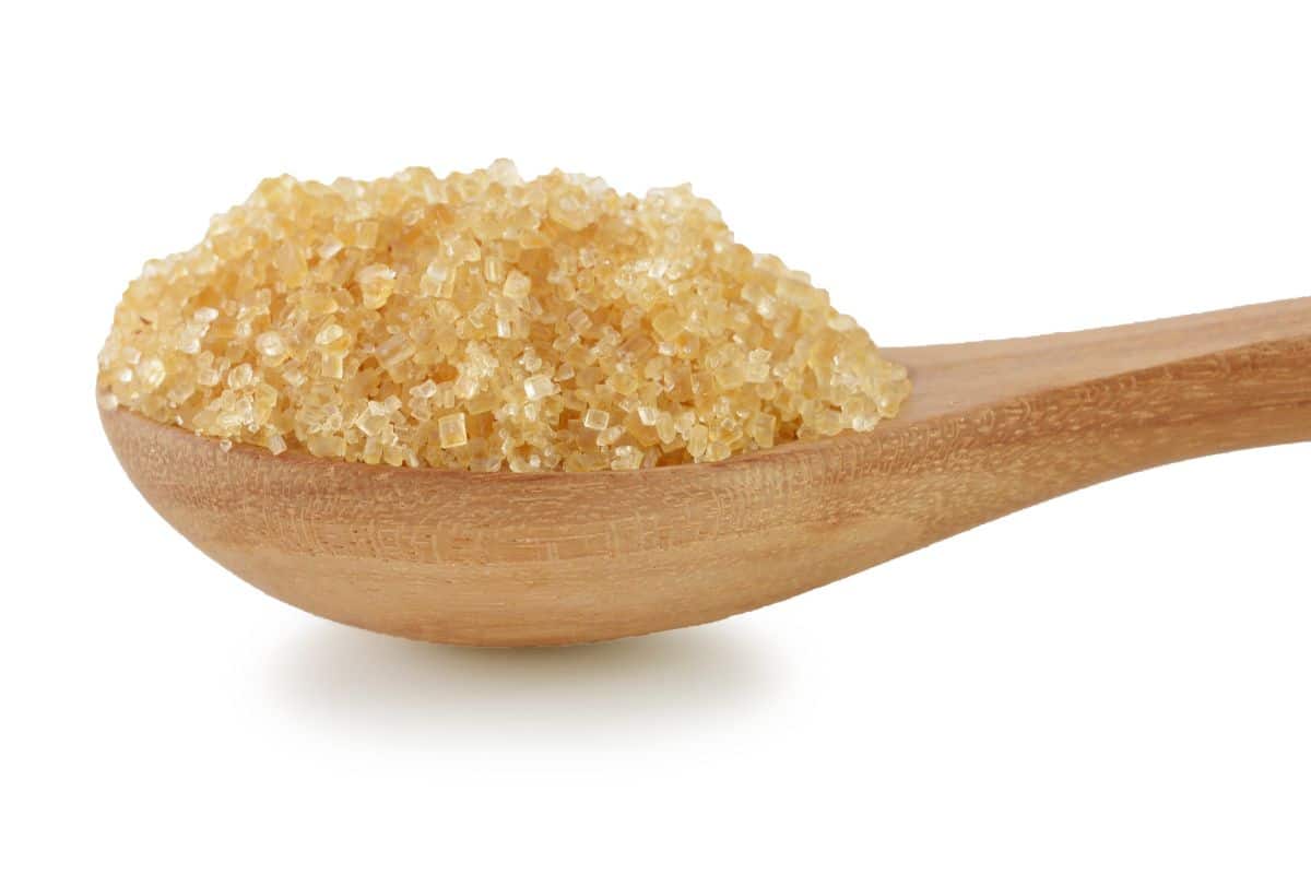 Demara sugar in a wooden spoon on a white background.