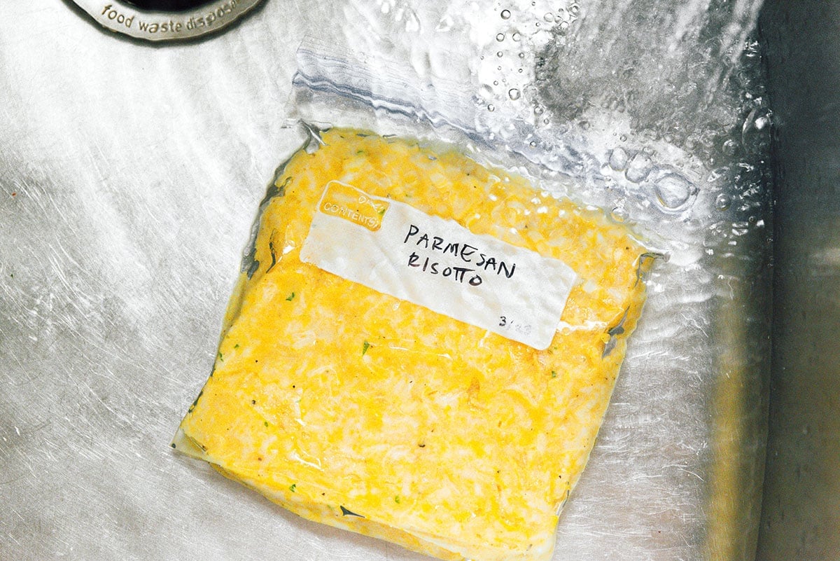A bag of frozen risotto being thawed in warm water.