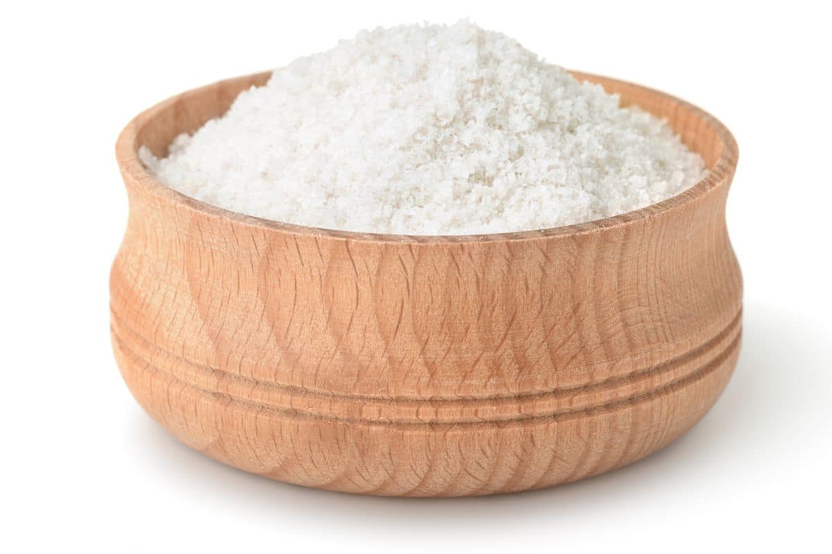 Kosher salt in a wood bowl on a white background.