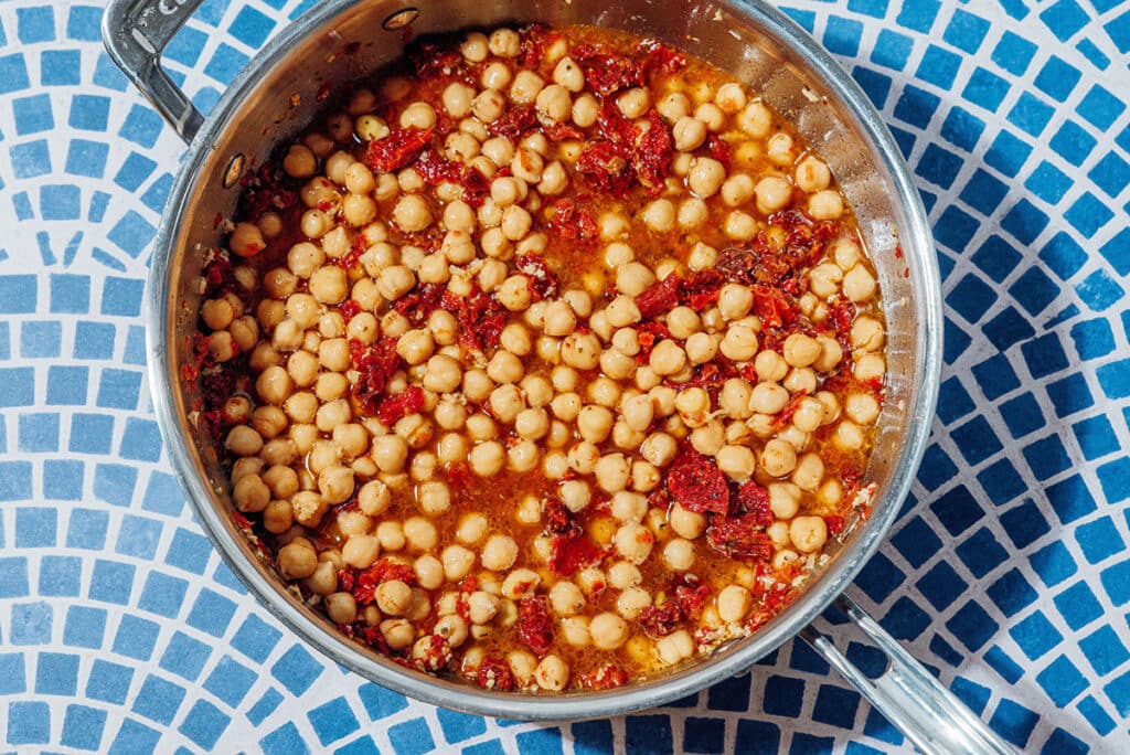 Chickpeas and sun dried tomatoes in a pan.