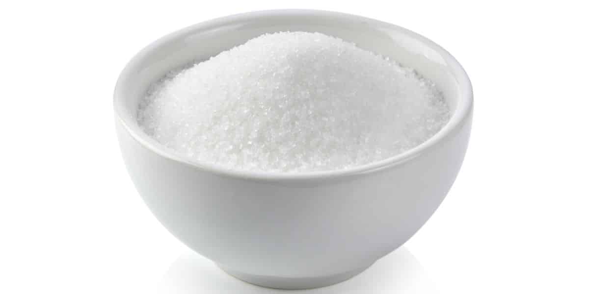 White sugar in a bowl on a white background.
