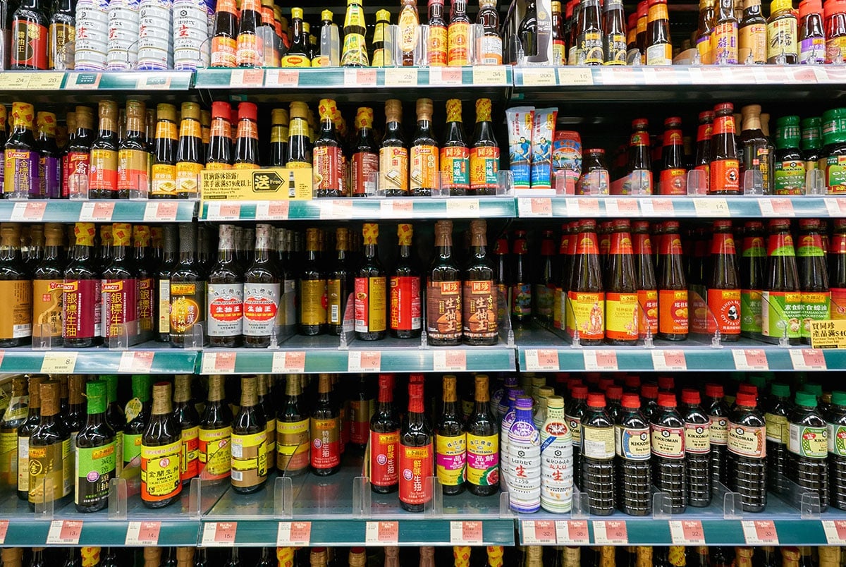 Many soy sauce bottles on a shelf.