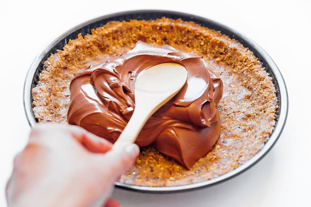 Spooning vegan chocolate mousse into pie dish.